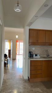 a kitchen with wooden cabinets and a living room at Family Apartment in Nea Moudania