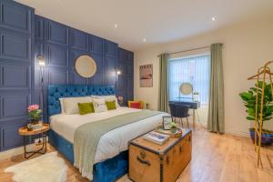 Dormitorio azul con cama y mesa en Regency Basement Apartment en Cheltenham