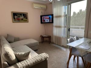 uma sala de estar com um sofá, uma mesa e uma televisão em Sunset Sea View - Beachfront Balcony - AC - Wifi em Durrës
