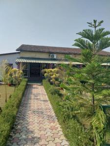 a walkway in front of a house with a palm tree at Jim Corbett Tiger Resort in Belparāo