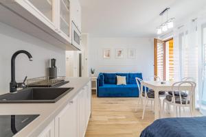 uma cozinha e sala de jantar com um sofá azul em Apartamenty Mierzeja NCNK Stegna Park Standard- 500 m do plaży em Stegna