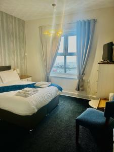 a bedroom with a bed and a window with blue curtains at The Wash & Tope in Hunstanton