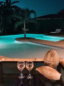 two glasses of wine on a table next to a swimming pool at GOUAPA by LES VILLAS KASSOUMAÏ à 100m de la plage in Ngaparou