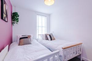 2 łóżka w pokoju z białymi ścianami i oknem w obiekcie Large 7 bedroom town house in Chester City Centre w mieście Chester