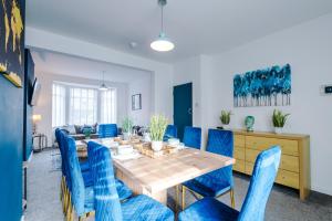 切斯特的住宿－Large 7 bedroom town house in Chester City Centre，一间带桌子和蓝色椅子的用餐室