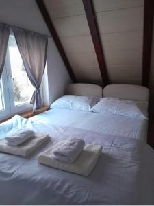 een wit bed met 2 handdoeken en een raam bij Vikendica Striček in Kupres