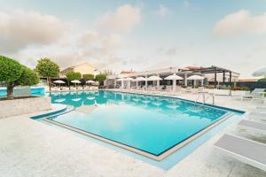 a pool with chairs and umbrellas at a resort at Diana Palace Hotel Zakynthos in Argasi