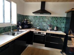 a kitchen with black cabinets and green tiles at Les panoramiks des Makes in Saint-Louis