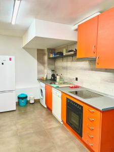 eine Küche mit orangefarbenen Schränken und einem weißen Kühlschrank in der Unterkunft Modular Suites Alfonso Gómez in Madrid