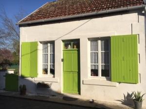 Cottage chaleureux face à l'étang في Précy: منزل أبيض وبه مصاريع خضراء ونافذة