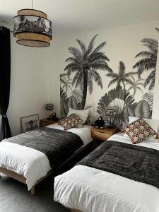 2 camas en una habitación con palmeras en la pared en Gite des Pommiers, en Sotteville