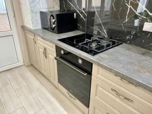 a kitchen with a stove and a microwave at Family Haven Apartment in Chişinău