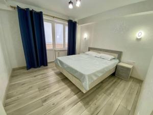 a bedroom with a bed with blue curtains and a wooden floor at Family Haven Apartment in Chişinău