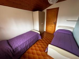 - une chambre avec 2 lits et une porte en bois dans l'établissement Appartamento Casa Vapi, à Pievepelago