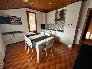 - une cuisine avec une table blanche et des chaises blanches dans l'établissement Appartamento Casa Vapi, à Pievepelago