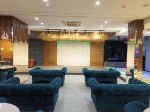 um quarto grande com sofás azuis e um palco em Ganeshwaram Hotel Sector-45 Noida em Noida