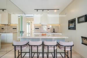 a kitchen with a bar with four stools at Oasis Smart Villa 3 Canggu in Canggu