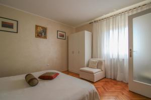 - une chambre avec un lit blanc et une chaise dans l'établissement Martinis A4, à Novigrad