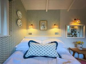 a bedroom with a white bed with a blue pillow at Shepherd's Hut at The Granary in Steyning