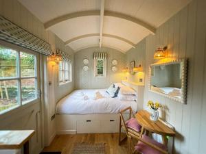 Shepherd's Hut at The Granary في ستيننج: غرفة نوم فيها سرير وطاولة فيها