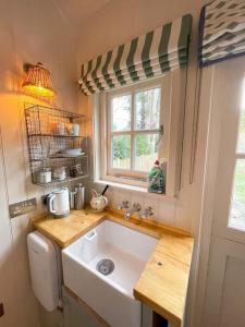 a small kitchen with a sink and a window at Shepherd's Hut at The Granary in Steyning