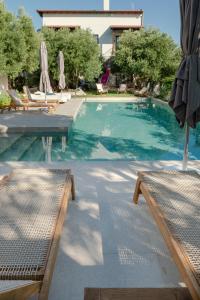 a swimming pool with chairs and umbrellas in a resort at MAISON - ELEA in Ierissos