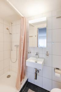uma casa de banho branca com um lavatório e um chuveiro em Bijou Sternen - Bergluft und Seeträume em Faulensee