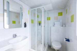 ein Bad mit einer Dusche, einem WC und einem Waschbecken in der Unterkunft ibis budget Angoulême Centre in Angoulême