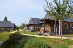 a log house with a porch and a tree at Les lodges de Sainte-Suzanne in Sainte-Suzanne
