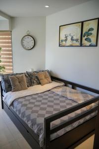un letto in una stanza con un orologio a muro di Dominiks Elegant Apt Ocean Views, Pool at Tambuli Resort 10 Floor a Maribago