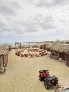 a red motorcycle parked in the sand in front of some huts at flamingo camp in Dār as Salām
