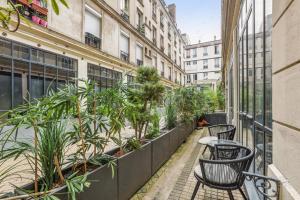 uma varanda com cadeiras e plantas num edifício em 142 Suite Ober - Superbe Appartement à Paris em Paris