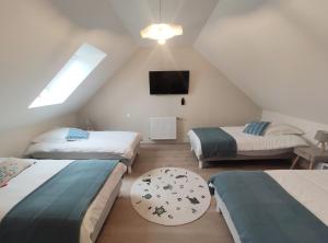 um quarto no sótão com 3 camas e uma televisão em L’ÉCHO DES VAGUES em Fort-Mahon-Plage