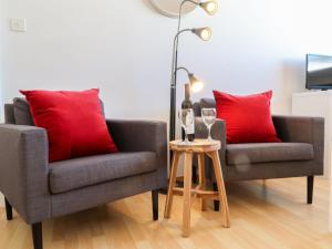 2 Stühle mit roten Kissen und einem Tisch mit Weingläsern in der Unterkunft Apartment Rosablanche C65 by Interhome in Siviez