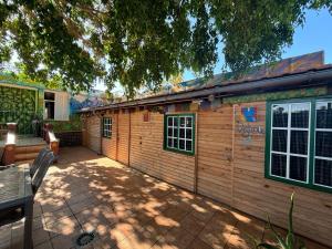 a wooden house with a patio and a table at Hostel Los Duendes del Sur in Costa Del Silencio