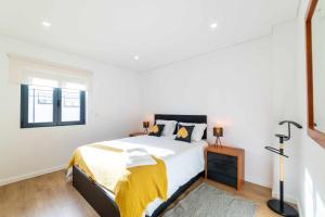 Un dormitorio blanco con una cama con una manta amarilla. en MY HOME IS YOUR HOME Viana House, en Viana do Castelo