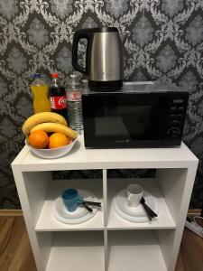 a microwave on a white cabinet with a bowl of fruit at Fair apartment 2 in Kelsterbach