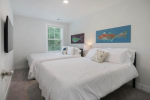 two beds in a bedroom with white walls at Lowcountry Lux 5 min to Beach 7 min to Dtwn in Charleston