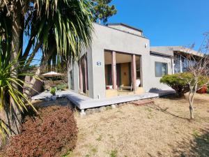 a white house with a porch and a palm tree at Hazen in Seogwipo