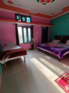 2 camas en una habitación con paredes moradas y verdes en gaurav home stay en Barkot