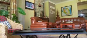 a living room with leather furniture and a table at Karibu Heritage House in Arusha