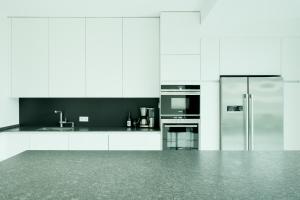 a white kitchen with white cabinets and a refrigerator at Lux.41 in Berlin