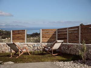 two chairs and a table in the grass next to a wall at Ocean Luxury Villas in Volimes +68 photos