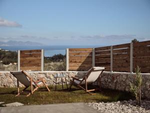 two chairs and a table in the grass next to a wall at Ocean Luxury Villas in Volímai