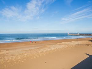 ein Strand mit Menschen, die auf dem Sand und dem Meer spazieren in der Unterkunft Apartment Le Grand Large by Interhome in Capbreton