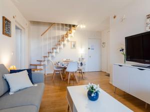 - un salon avec un canapé, une télévision et une table dans l'établissement Apartment Le Garden Fleuri by Interhome, à Blonville-sur-Mer