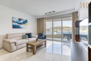 a living room with a couch and a table at Waterfront 3BR home, with private balcony by 360 Estates in St. Paul's Bay