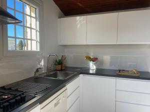 a kitchen with white cabinets and a sink and a window at Holiday Home Les Rosiers Grimpants by Interhome in Le Grau-du-Roi