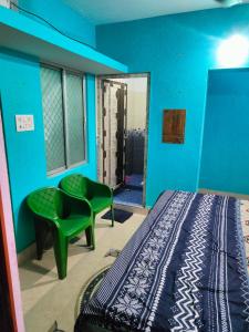 a bedroom with a bed and a green chair at jharana guest house in Puri
