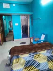 a bedroom with a bed and a blue wall at jharana guest house in Puri